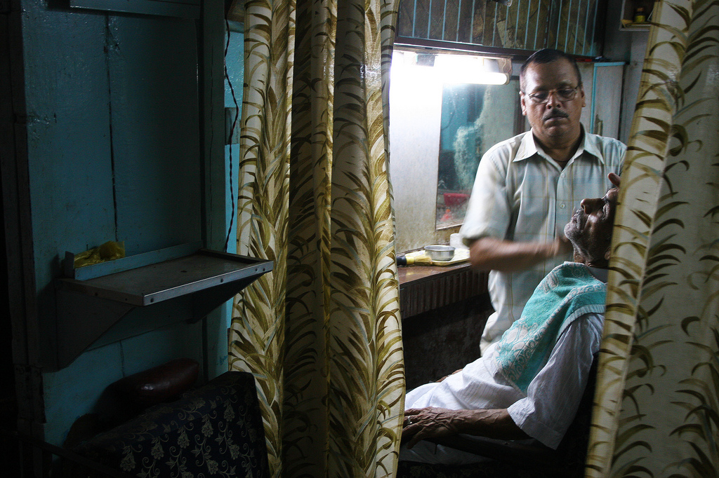 A man getting a shave at a local barber shop in Varanasi, India.