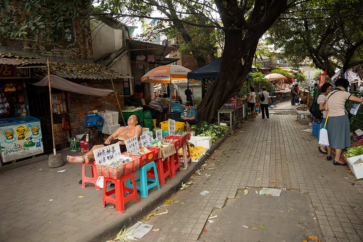 A typical street scene in Guangzhou: A street vendor sleeping at Huayuan market.