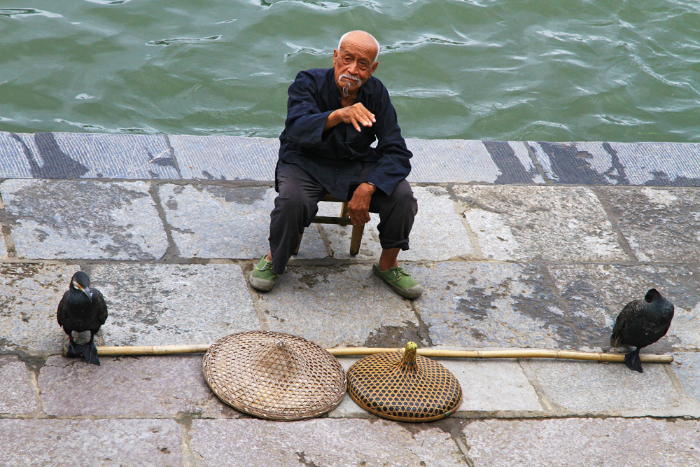 A fisherman with his Cormorant waiting for customers.