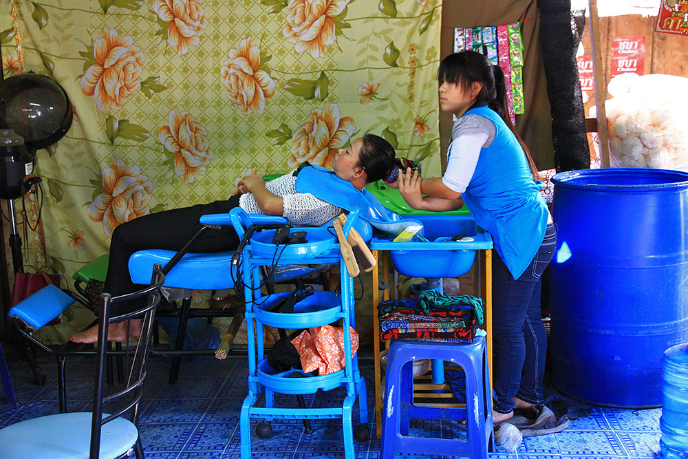 A hairdresser at the bus station in Laos.