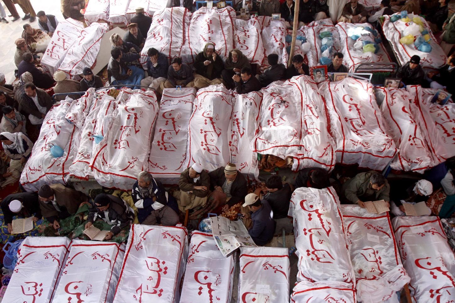 Associated Press/Arshad Butt - Pakistani Shiite Muslims sit in protest next to the dead bodies of their family members killed in Saturday's bombing