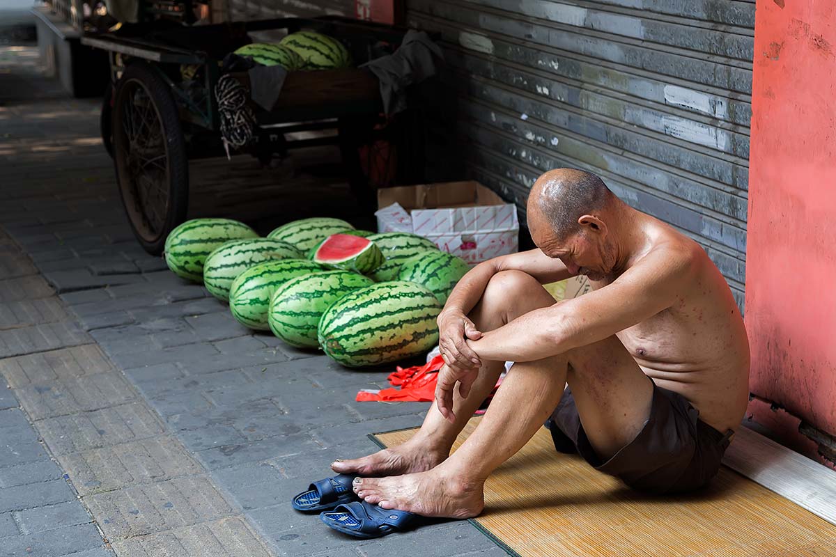 Shirtless Chinese selling watermelons in the streets of Beijing.