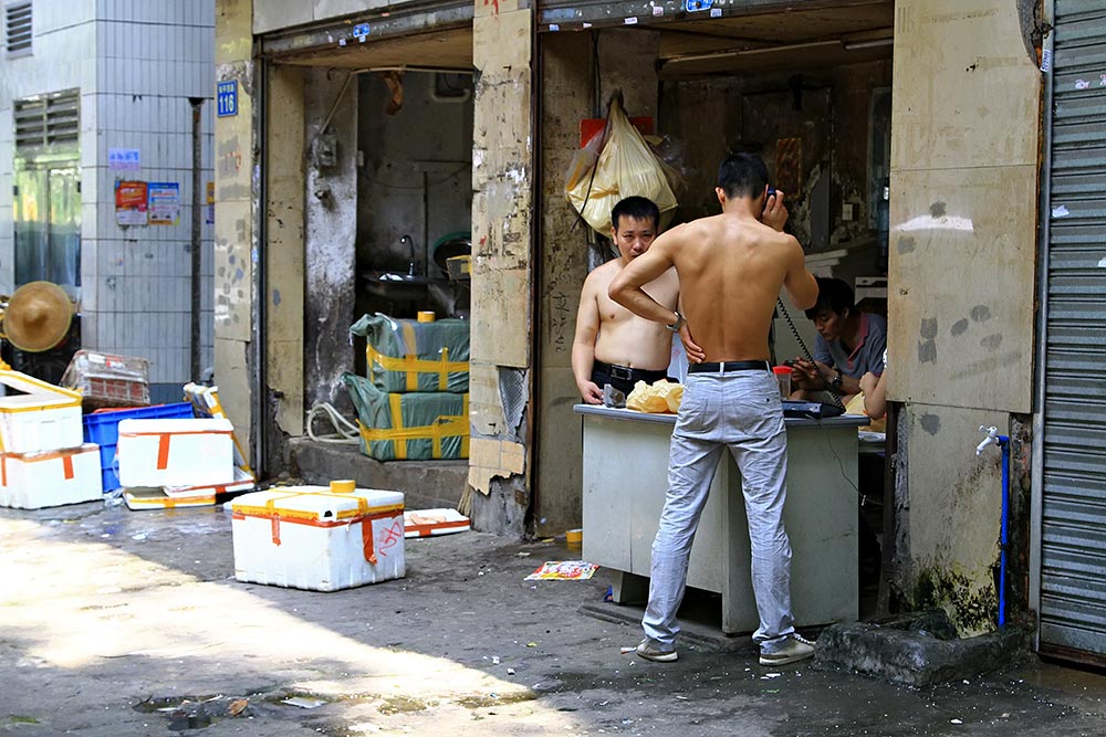 Chinese men without their T-Shirts in the middle of the street in Guangzhou, China.