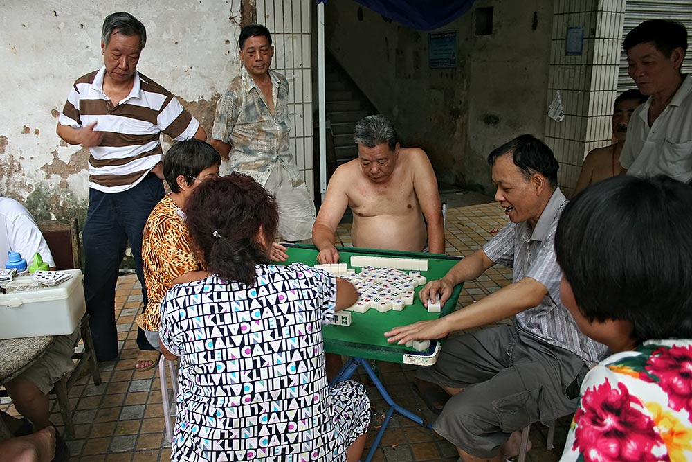 Chinese men without their T-Shirts on playing Mahjong in Guangzhou, China. Shirtless Chinese man playing a game of Mahjong in Guangzhou.