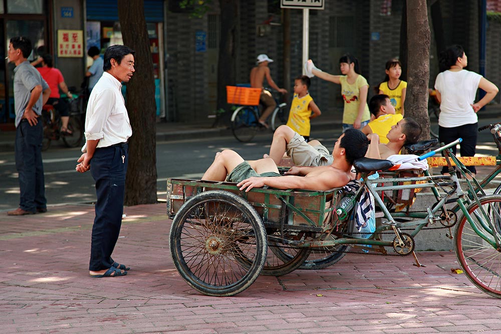 Shirtless men resting in the streets of Guangzhou, China.