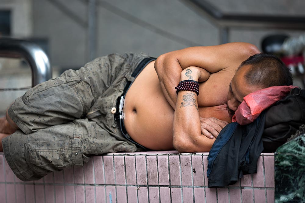 Shirtless Chinese man sleeping in the streets of Guangzhou.