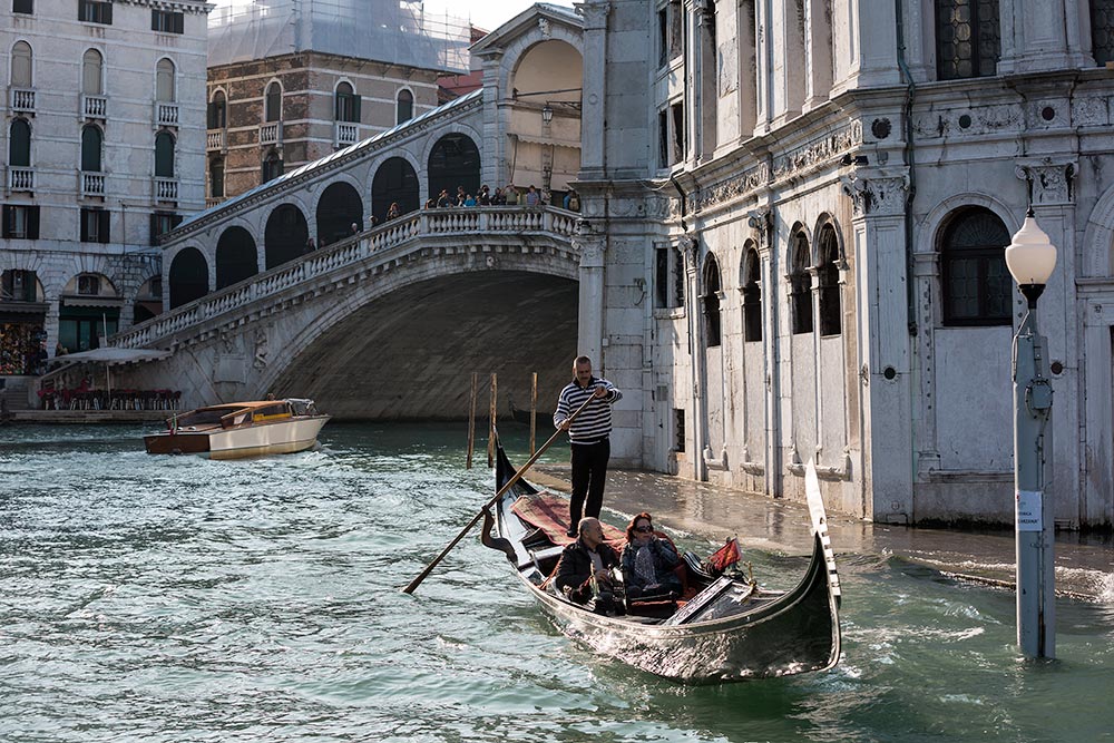 The Rialto Bridge in Venice, Italy. The Rialto Bridge in Venice is one of the four bridges spanning the Grand Canal in Venice, Italy. It is the oldest bridge across the canal, and was the dividing line for the districts of San Marco and San Polo.