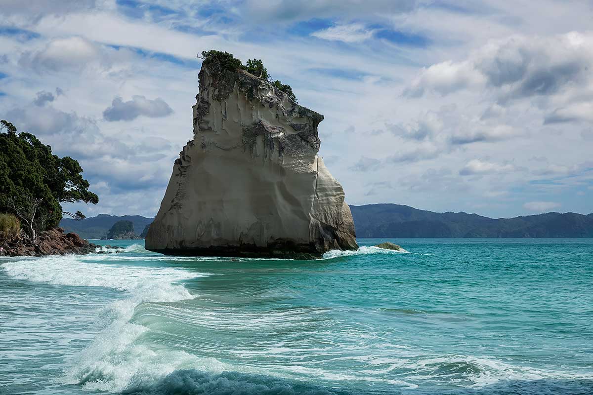 The striking rock known as 'Te Hoho'. Just off the beach at Cathedral Cove is a large pinnacle of pumice breccia. Over centuries this has been sculpted by wind and water - it now looks like the prow of a large ship steaming into the beach. The striking rock known as 'Te Hoho'. Just off the beach at Cathedral Cove is a large pinnacle of pumice breccia. Over centuries this has been sculpted by wind and water - it now looks like the prow of a large ship steaming into the beach.