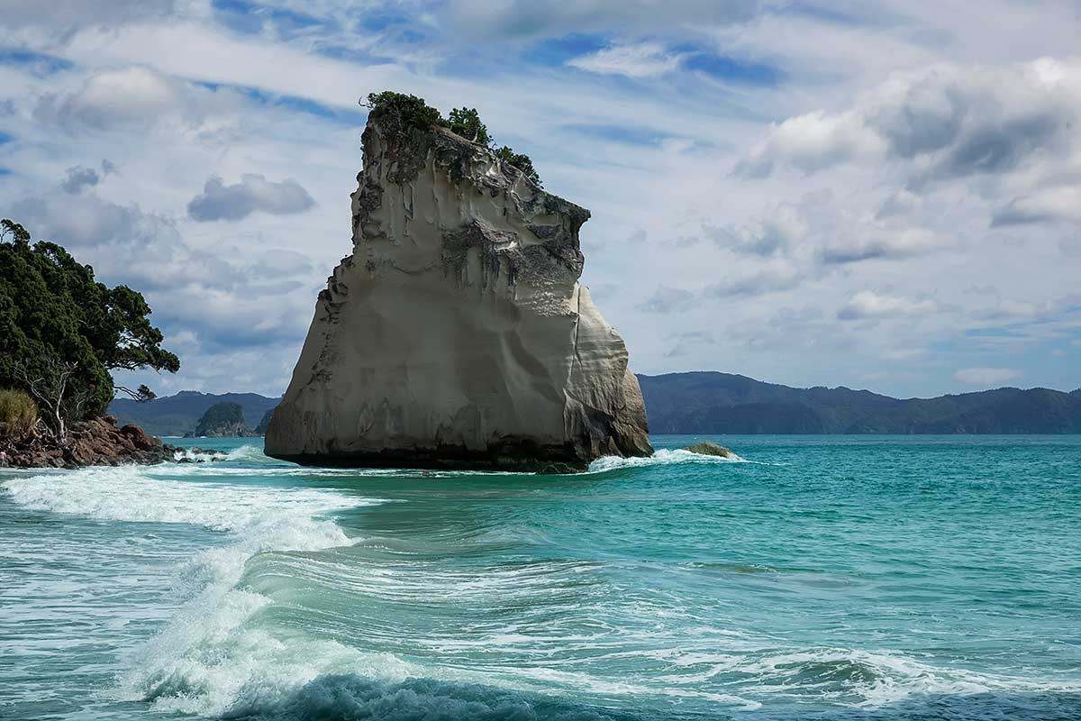 The striking rock known as 'Te Hoho'. Just off the beach at Cathedral Cove is a large pinnacle of pumice breccia. Over centuries this has been sculpted by wind and water - it now looks like the prow of a large ship steaming into the beach.