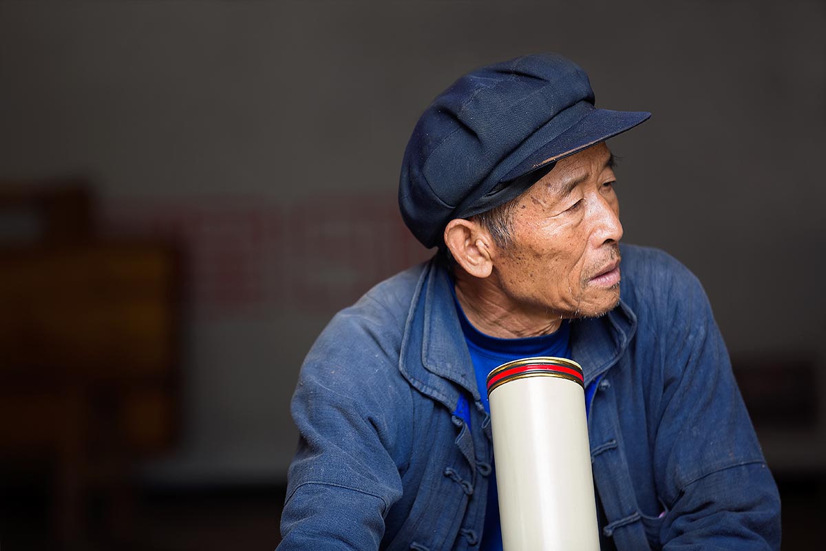 A local Chinese smoking a pipe in the old town of Xinjie.